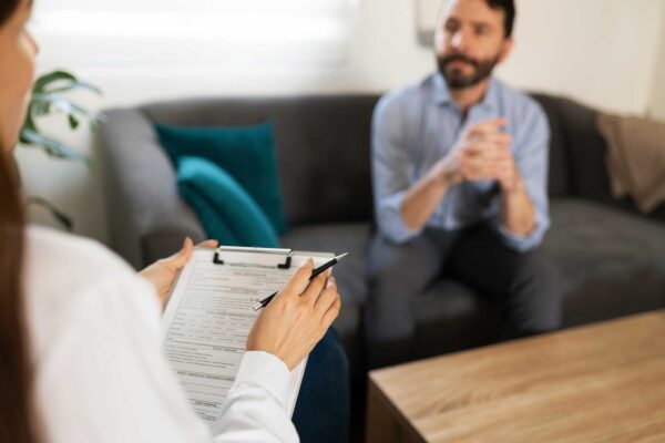 therapist holding a clipboard as she meets with a client and discusses clinical psychology vs psychiatry