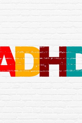 ADHD painted on a white brick wall. every letter is a different color